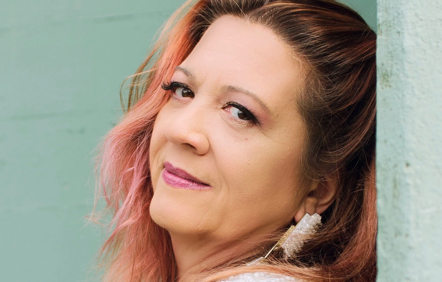 A portrait of the artist leaning back against a colorful wall.